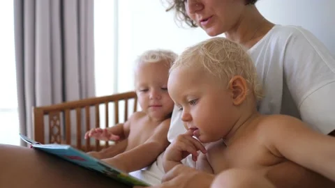 Quality time of a single mom with her baby twins. Reading together as a learning Video stock 153458656