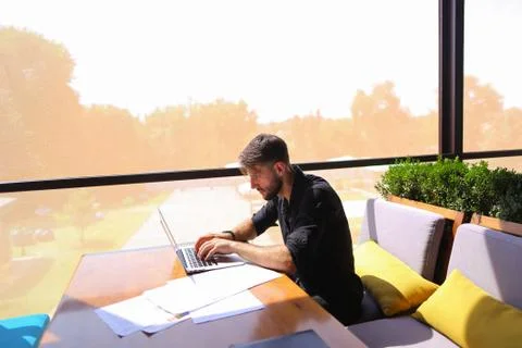 Quantity surveyor working at cafe table with papers and laptop. 스톡 사진