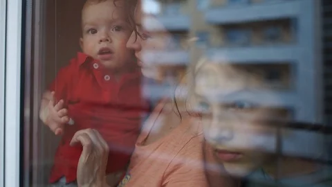 Quarantine and self-isolation concept. Family near the window behind the glass Stock Footage 129162851