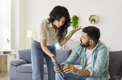 Quarrel of couple over smartphone using at home, wife shouting scolding husband Fotos Stock
