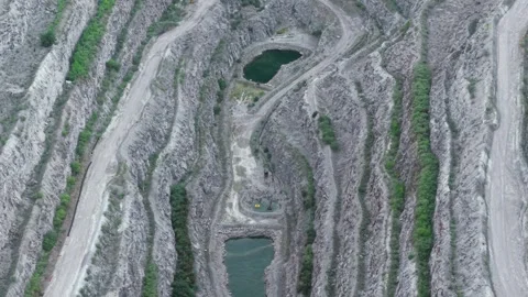 Quarry displaying layered rock cuts surrounding deep green pools. Excavation Stock Footage 315656742