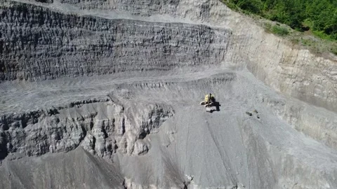 Quarry on a hill slope with an excavator digging stone, aerial drone view. Video stock 336664292