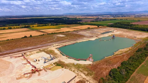 Quarry lake with floating dredgers and shoreline conveyors. Mining structures Stock Footage 346483105