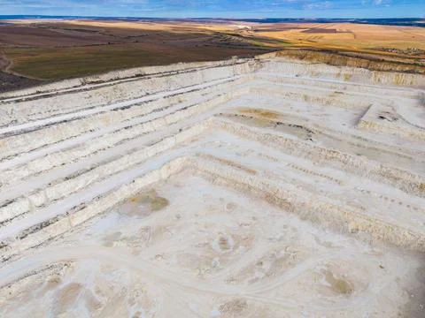 Quarry in a large open area showing layers of earth and machinery observed .. Stock Photos