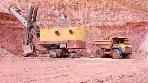 In a quarry, a loaded mining truck is driving away from a mining excavator. Stock Footage 122217907
