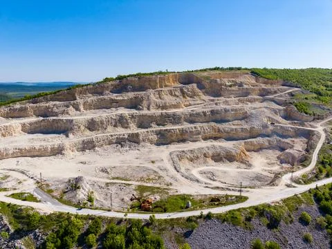 The quarry shows multiple layers of stone cut into the earth. A road runs alo Stock Photos