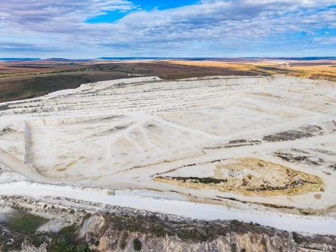 Quarry site with large open area and rough terrain during daytime under a c.. Stock Photos