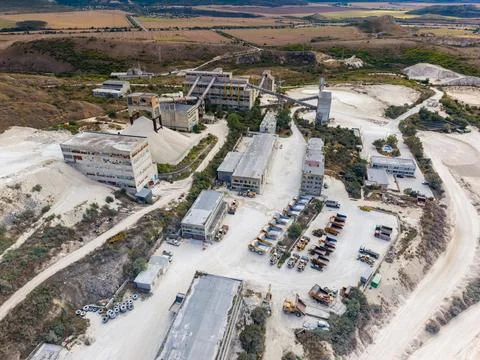 Quarry site with processing buildings and vehicles in a rural landscape dur.. Stock Photos