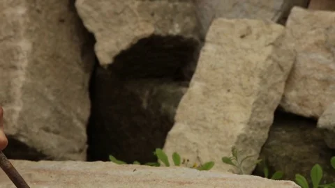 A quarryman or stonemason is drilling a stone with a chisel and a hammer. Stock Footage