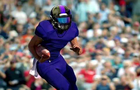Quarterback running with spectator in background Stock Photos