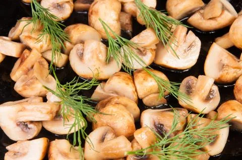 Quartered roasted champignons with dill Stock Photos