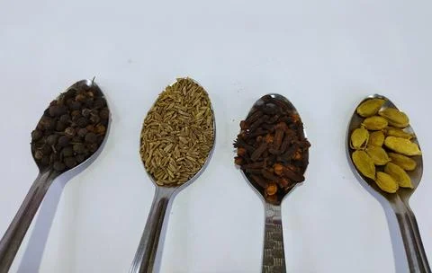 A Quartet of Whole Spices Pepper, Cumin, Cloves, and Cardamom on Spoons Stock Photos
