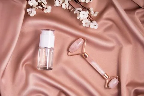 Quartz roller and cometic product on shiny pink fabric. Stock Photos