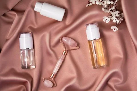 Quartz roller and cometic products on shiny pink fabric. Stock Photos