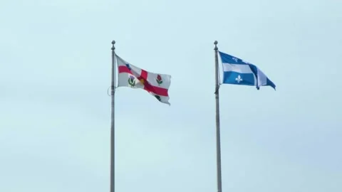 Quebec and Canadian flags flying side by side above the city Vidéo 343718715