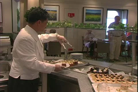 QUEEN MARY 2, 2004, Ocean liner, steward picks up desserts from buffet Stock Footage 20447899
