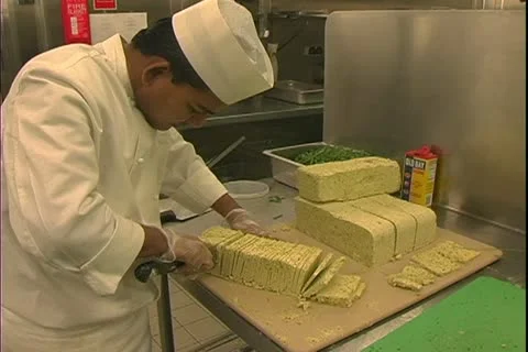Queen Mary 2 ocean liner, galley, kitchen, chefs slicing cheese Stock Footage