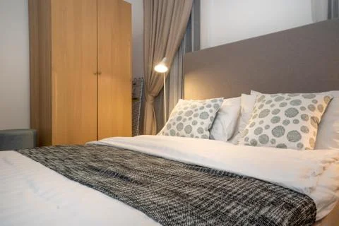 Queen size bed with bed runner and reading lamp in villa, house and apartment Stock Photos