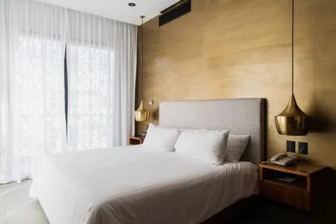 Queen size bed with bed runner and reading lamp in villa, house and apartment Stock Photos