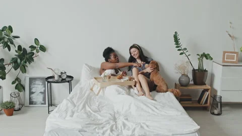 Queer Couple Eating Breakfast in Bed and Petting Dog Video stock 159596454