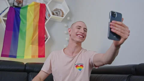 Queer non-binary bald influencer waves to his followers on social media with Stock Footage 178166756