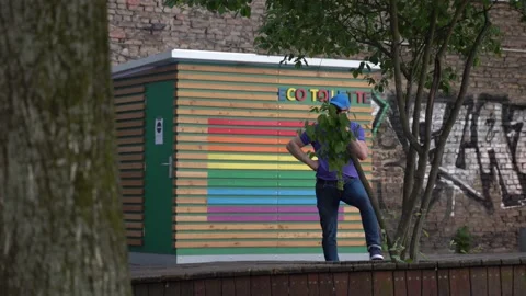 Quer man standing in front of rainbow city toilet in Berlin, Germany Stock Footage 159664118