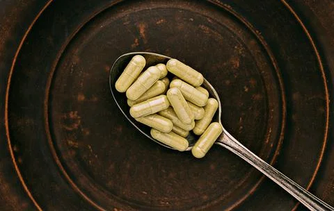 Quercetin capsules on a spoon on a clay plate. mental wellbeing and personal 스톡 사진