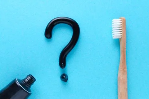 Question from black toothpaste, teeth care concept, wooden toothbrush on blue Stock Photos