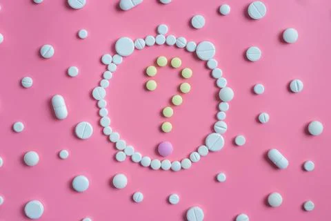 The question mark consists of tablets and white pills on pink background Stock Photos