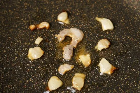 A question mark cut from lard is fried in a frying pan, unhealthy food. Stock Photos