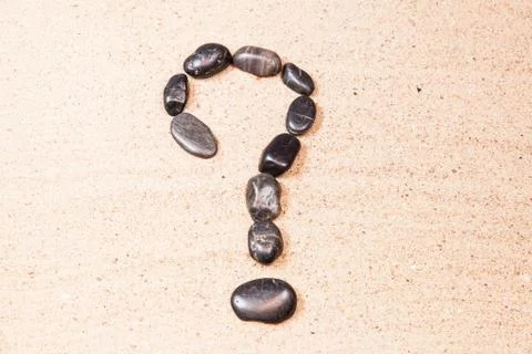 Question mark drawn with pebbles on the sand of a beach Stock Photos