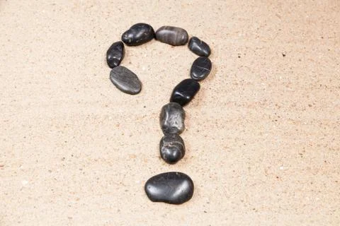 Question mark drawn with pebbles on the sand of a beach Stock Photos