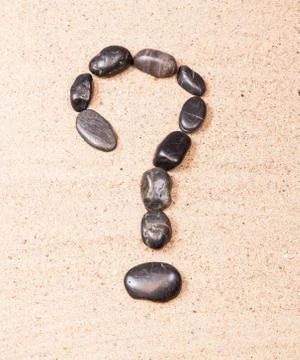 Question mark drawn with pebbles on the sand of a beach Stock Photos