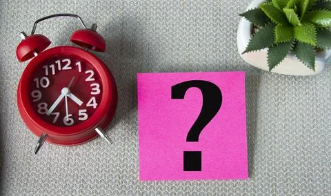 Question mark on note sheet on gray background with alarm clock and cactus Stock Photos