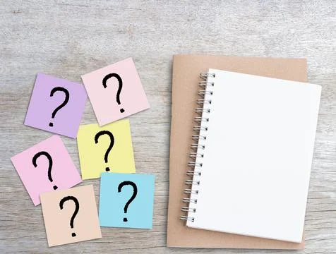 Question mark on pink sticky notes and blank notebook on wood table Stock Photos