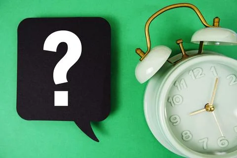 Question mark text on speech bubble with alarm clock on green background Stock Photos