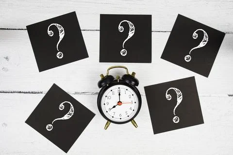 Question Mark text written on sticky note and alarm clcok flat lay on woode.. Stock Photos