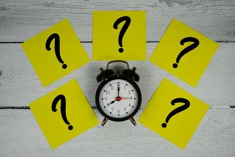 Question Mark text written on sticky note and alarm clcok flat lay on woode.. Stock Photos