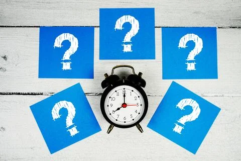 Question Mark text written on sticky note and alarm clcok flat lay on woode.. Stock Photos