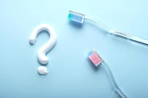 A question mark toothpaste and a pair f toothbrushes on blue. Stock Photos