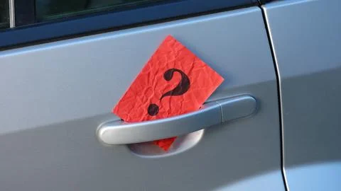 Question mark tucked behind the silver door handle of a gray car Stock Photos