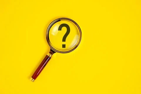 Question mark under magnifying glass, on yellow background. Stock Photos