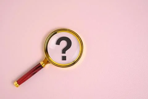 Question mark under magnifying glass, on pink background. Stock Photos