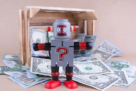 Question mark written on standing robot with wooden money crate Stock Photos