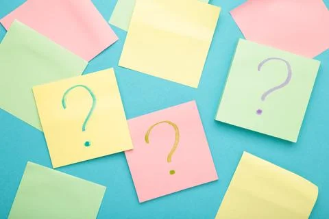 Question marks on colour stickers on blue background. Top view. Stock Photos