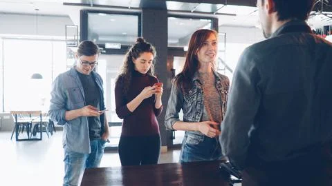 Queue of cheerful young people standing in coffee-house in the morning and Stock Photos