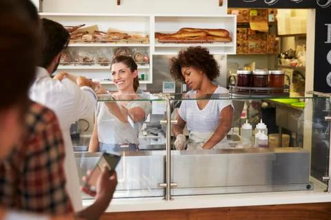 A queue of customers served by two women at a sandwich bar Stock Photos