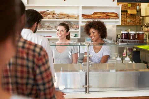 A queue of customers served by two women at a sandwich bar Stock Photos