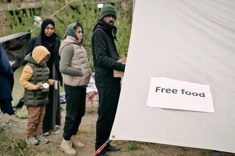 Queue of migrants standing in front of volunteering tent Stock Photos