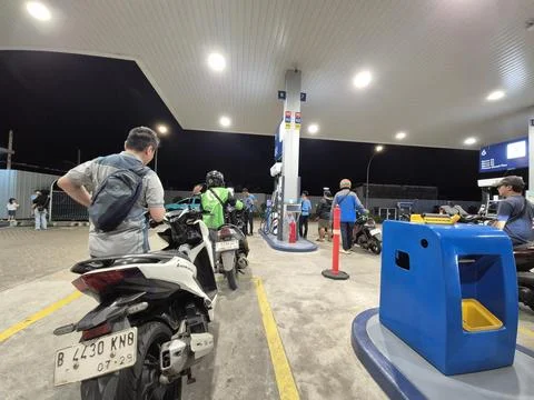 Queue of motorcyclists and a ride-hailing driver refueling at a Vivo gas st.. Stock Photos